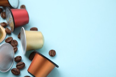 Many coffee capsules and beans on light blue background, closeup. Space for text