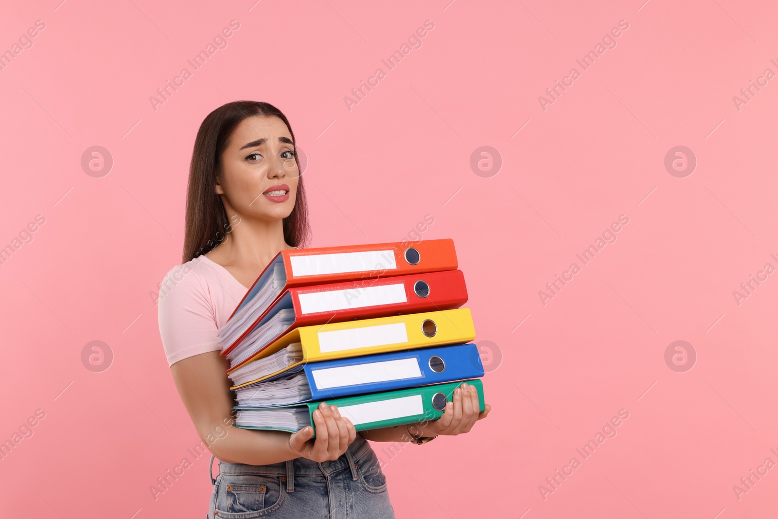 Photo of Frustrated woman with folders on pink background, space for text