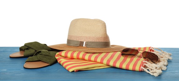 Photo of Beach towel, slippers, straw hat and sunglasses on light blue wooden surface against white background