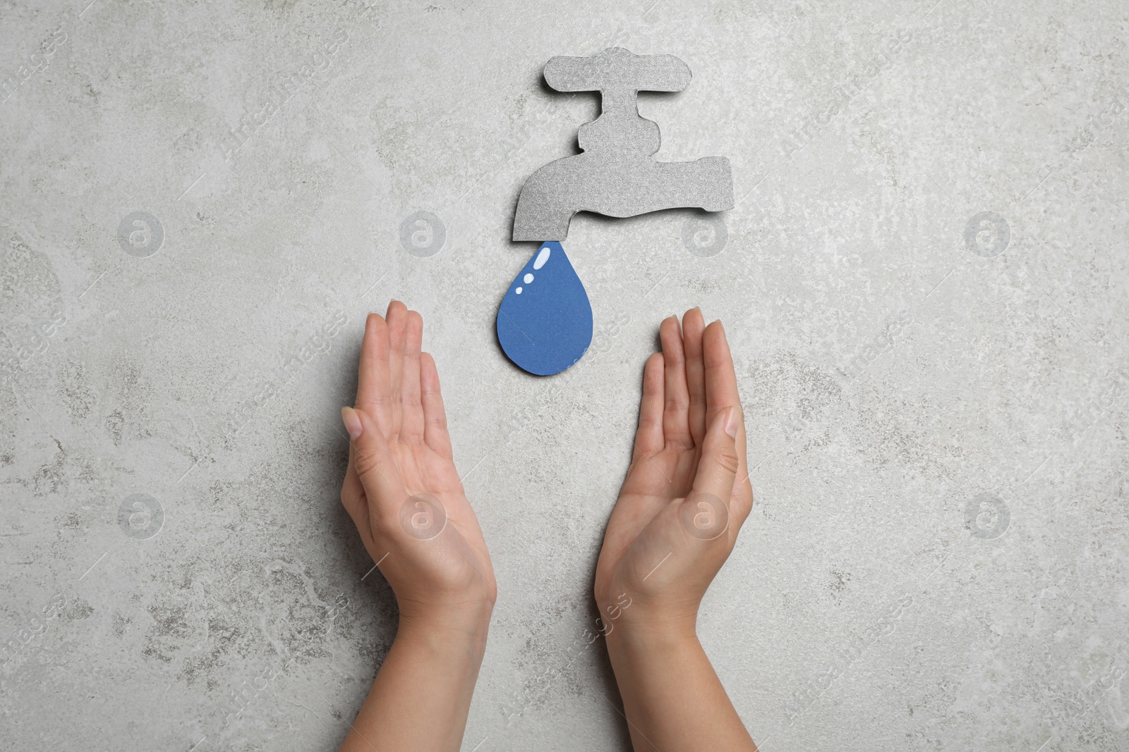 Photo of Save Water concept. Woman at light grey table with paper tap and drop, top view