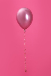 Bright balloon with ribbon on color background