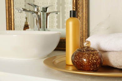 Photo of Toiletries and towels on white countertop near mirror in bathroom