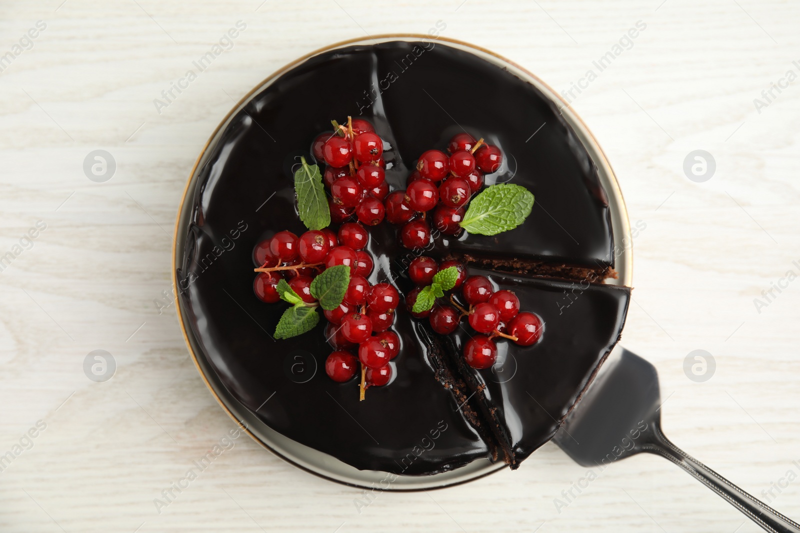 Photo of Tasty homemade chocolate cake with berries and mint on white wooden table, top view