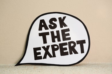 Photo of Paper message bubble with phrase Ask The Expert near beige wall