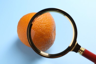 Photo of Cellulite problem. Zoomed orange peel on light blue background, view through magnifying glass