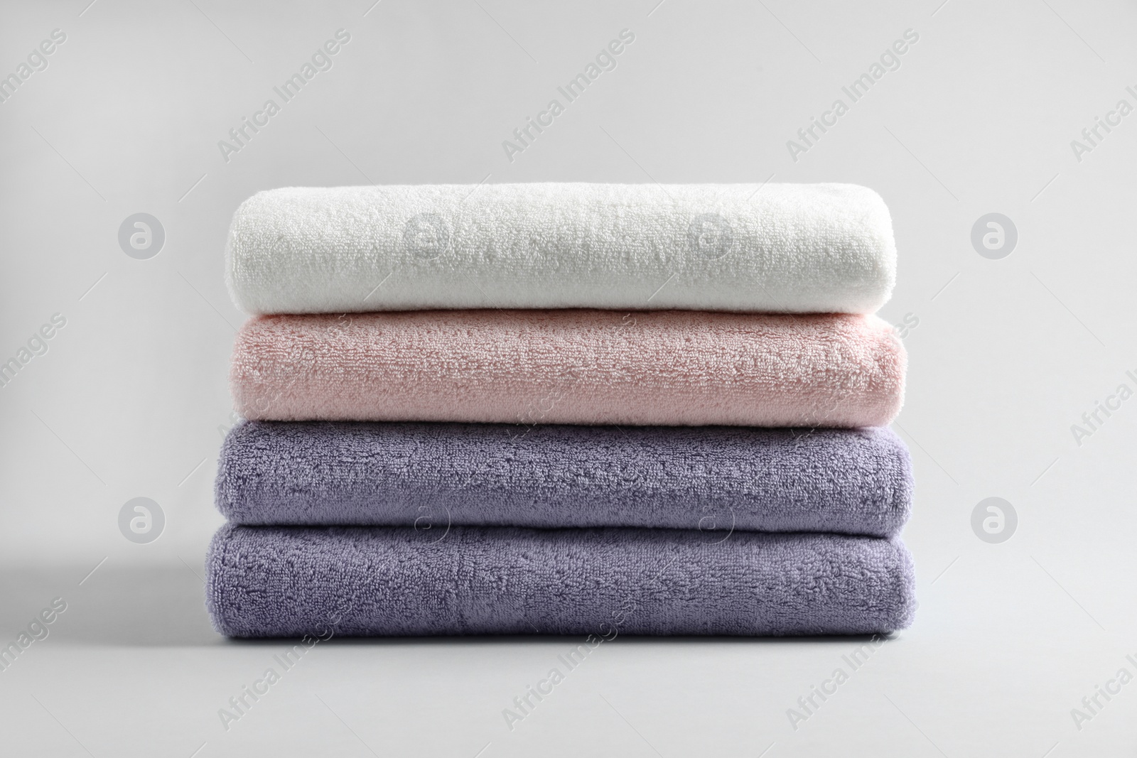 Photo of Stack of fresh fluffy towels on grey background