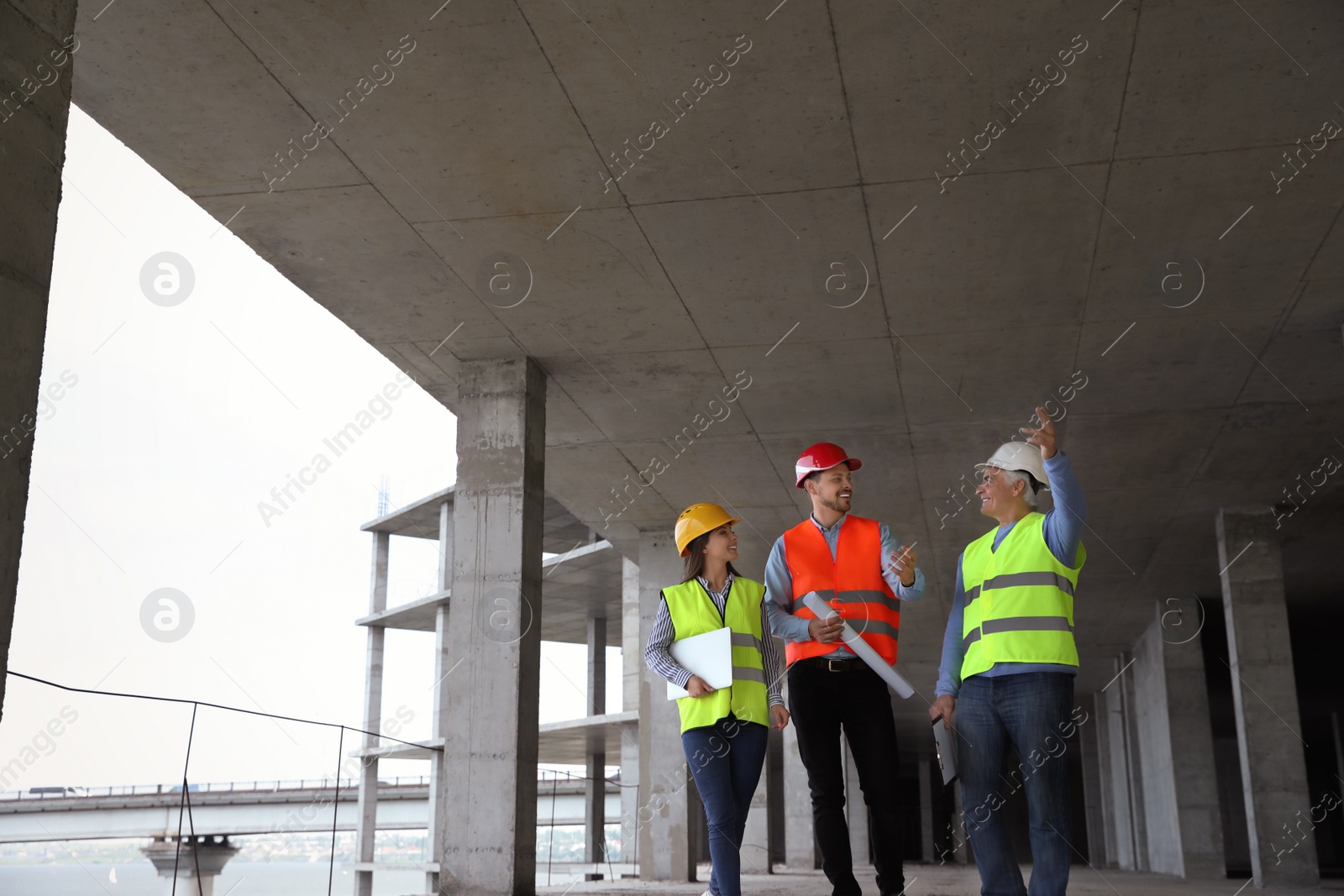Photo of Professional engineers in safety equipment at construction site. Space for text.