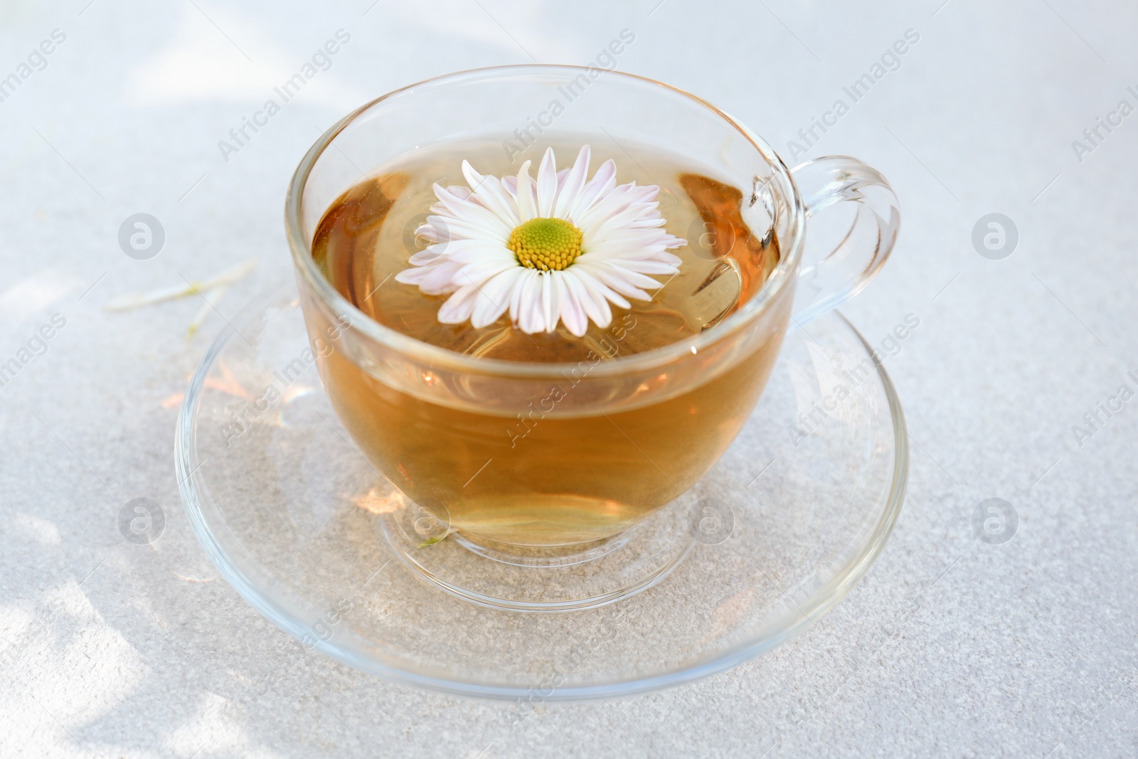 Photo of Glass cup of delicious chamomile tea on white table