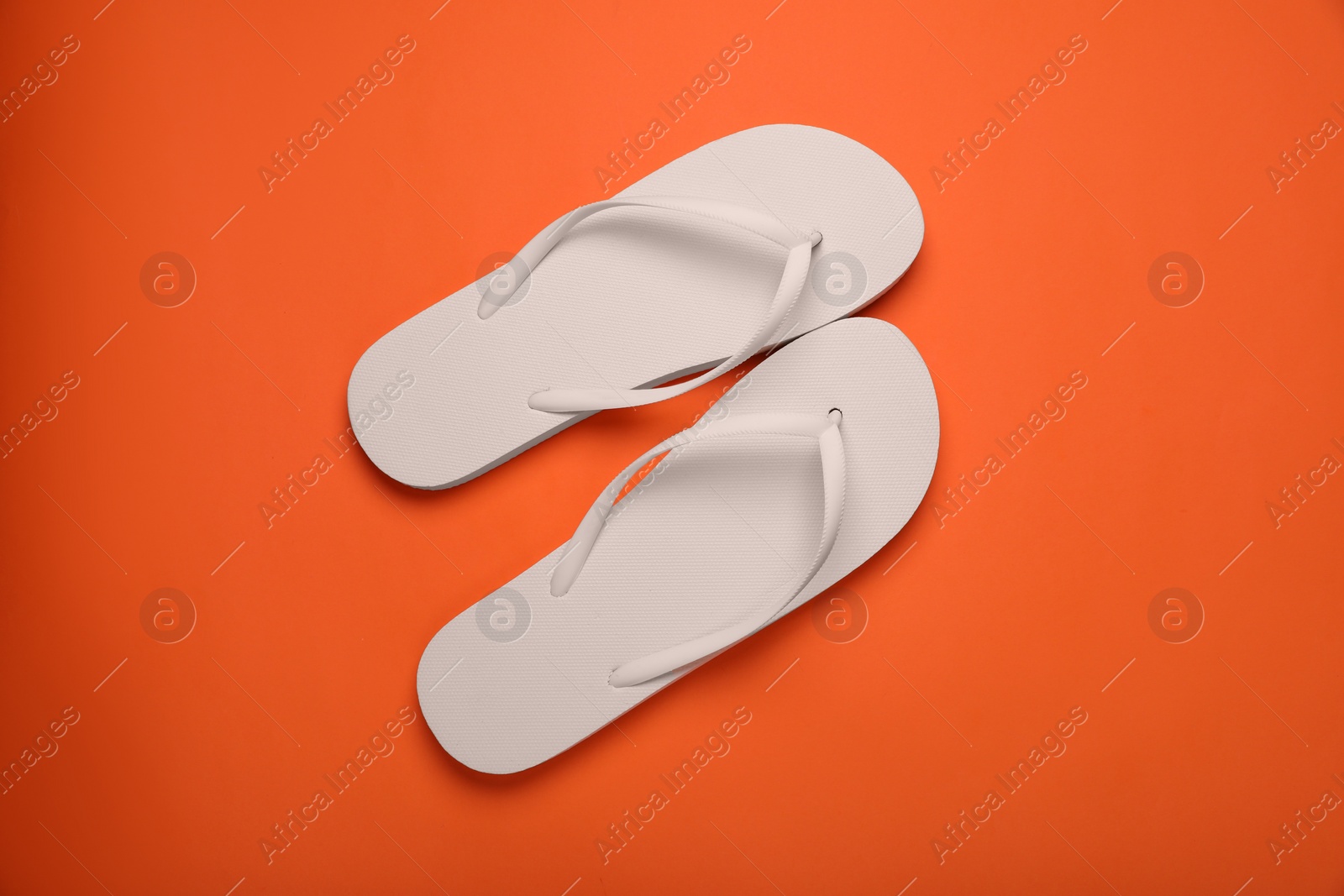 Photo of Stylish white flip flops on orange background, top view