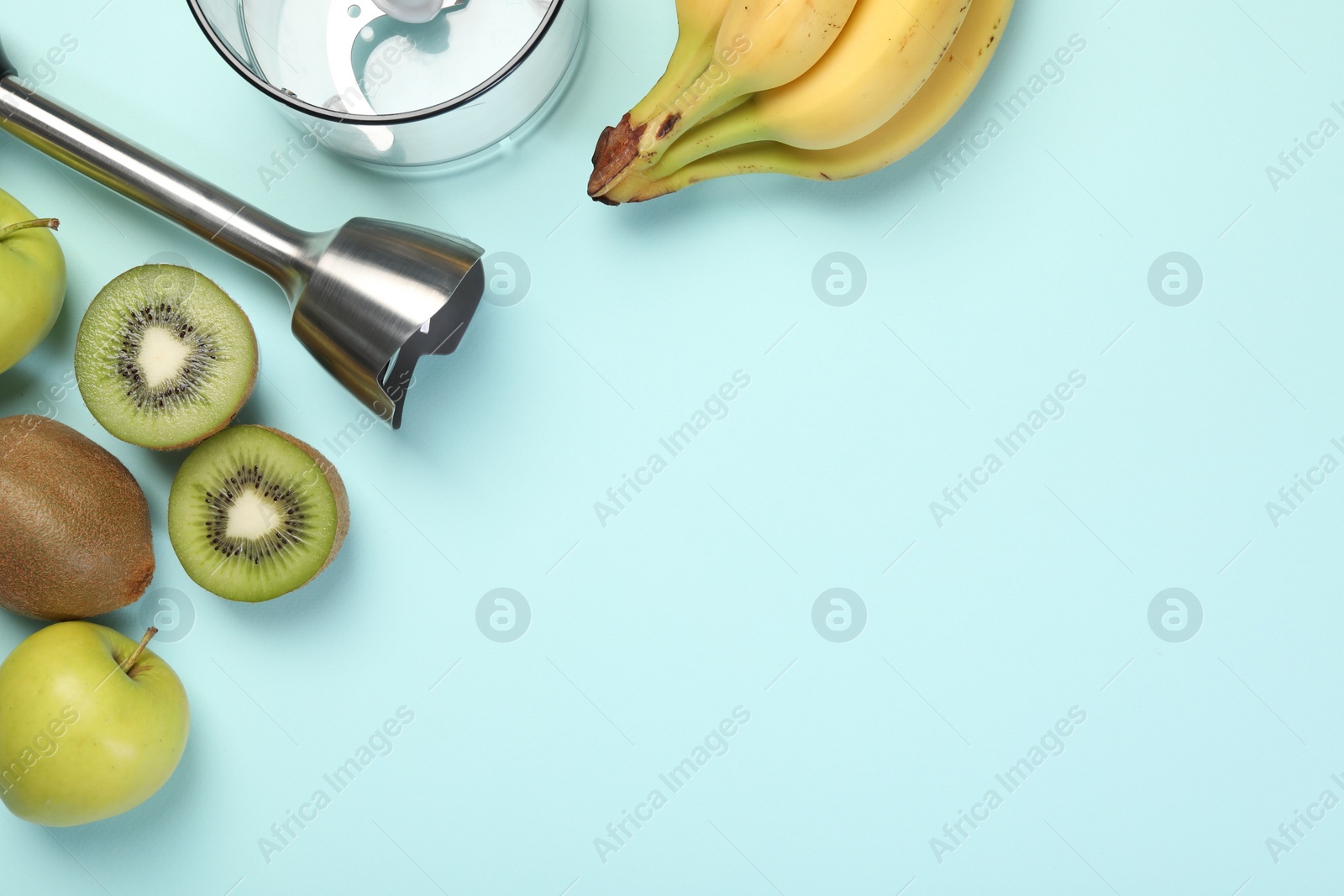 Photo of Hand blender kit and fresh fruits on light blue background, flat lay. Space for text