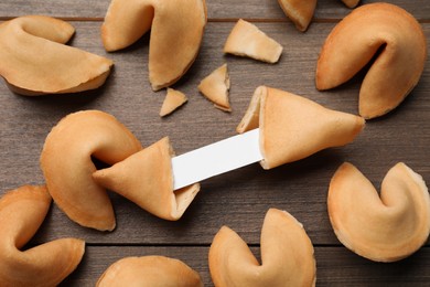 Tasty fortune cookies with predictions on wooden table, above view. Space for text