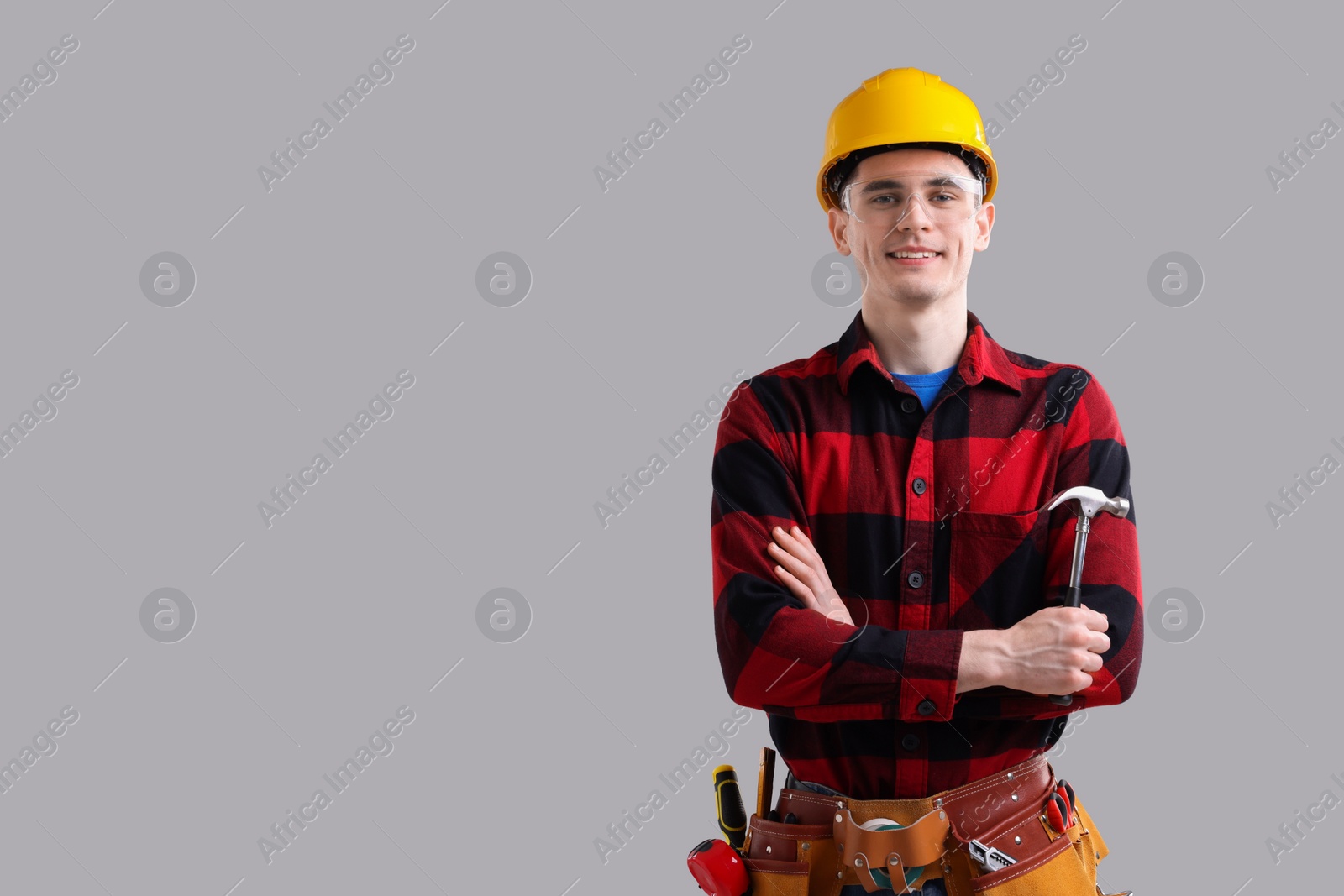 Photo of Professional repairman holding hammer on light grey background. Space for text