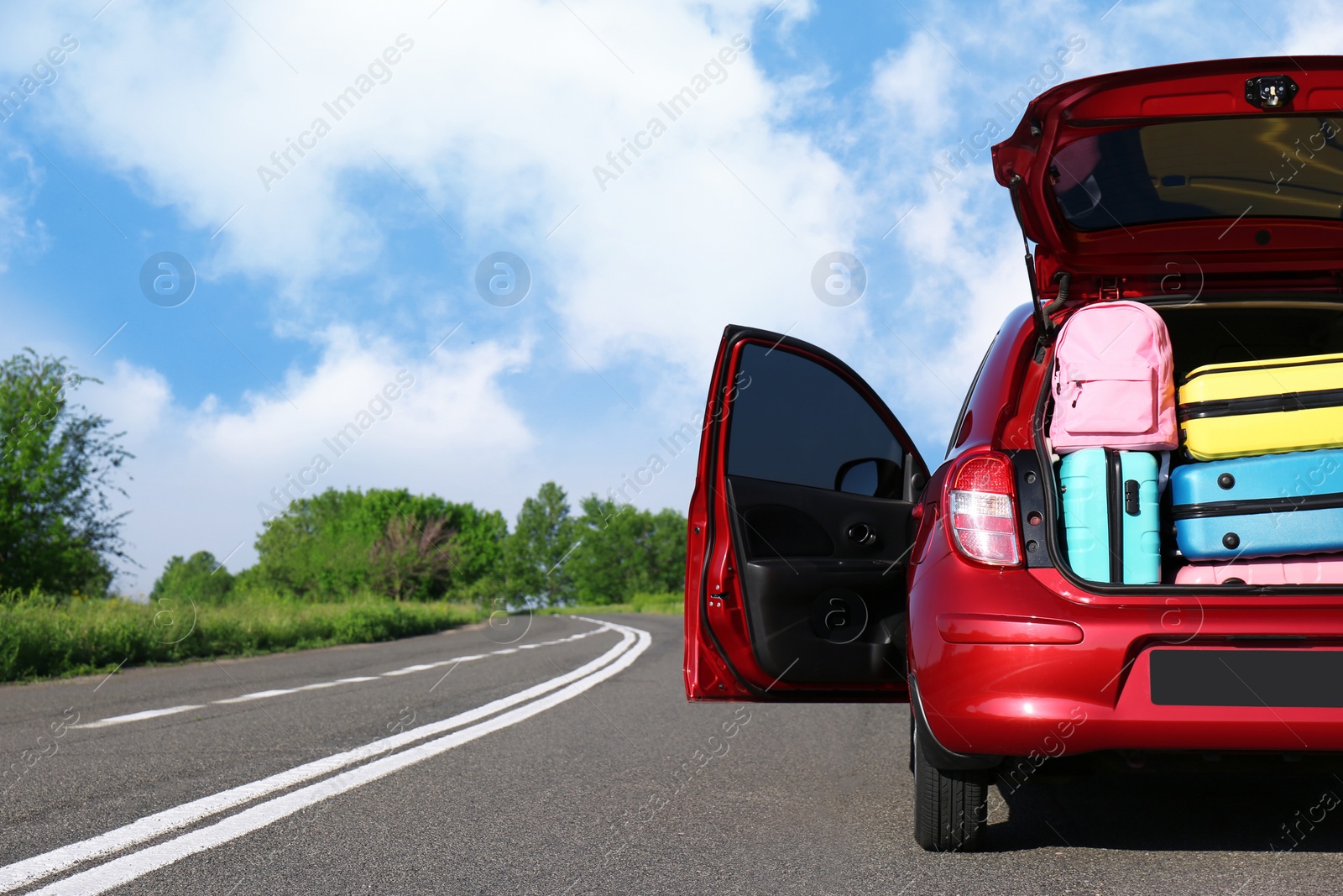 Photo of Family car with open trunk full of luggage on highway. Space for text