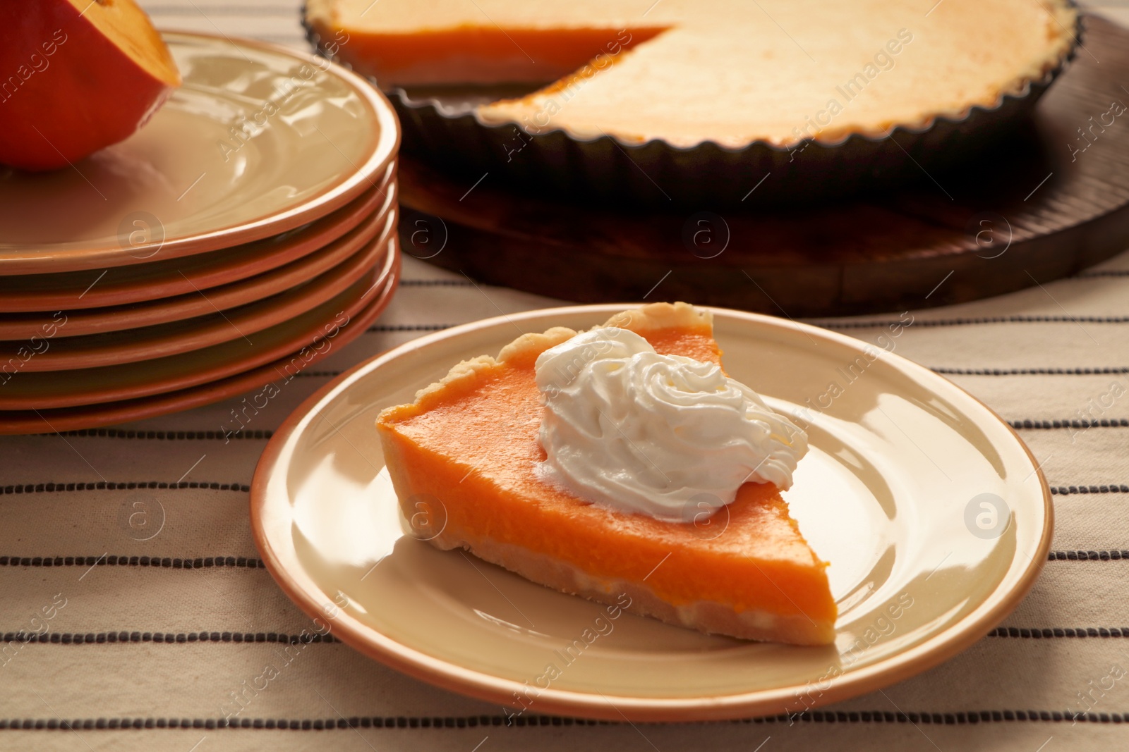 Photo of Piece of fresh homemade pumpkin pie with whipped cream on table