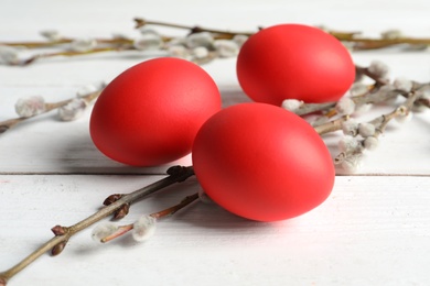 Photo of Red dyed Easter eggs and pussy willow on wooden table, closeup