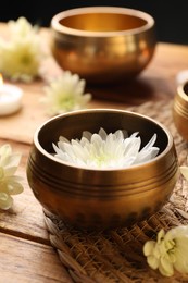 Photo of Tibetan singing bowls and beautiful chrysanthemum flowers on wooden table