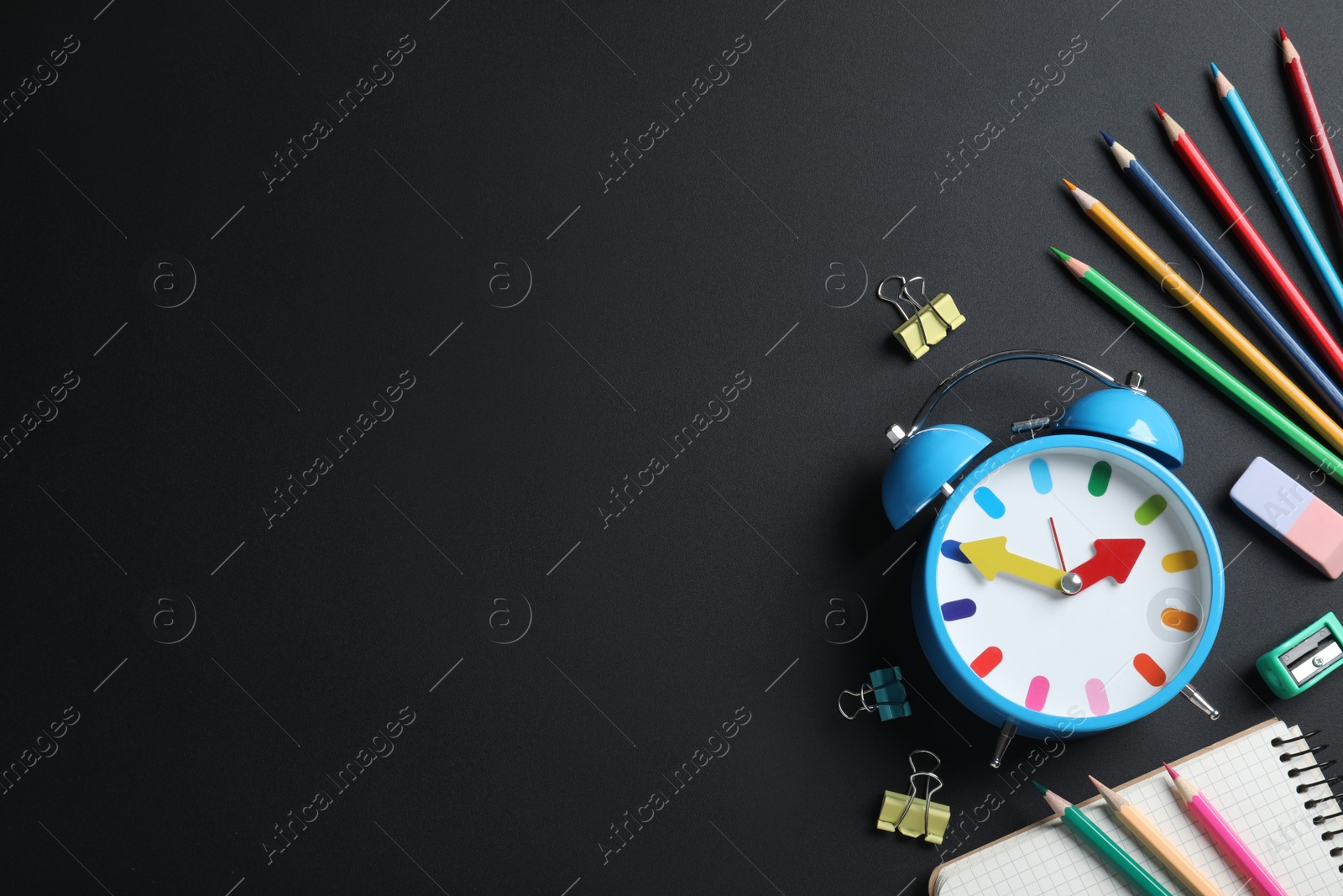 Photo of Flat lay composition with alarm clock and different stationery on black background, space for text. School time