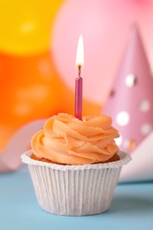 Photo of Tasty birthday cupcake with candle on light blue table, closeup