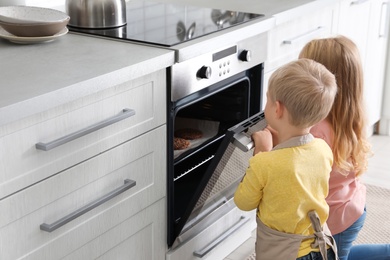 Little kids baking something in oven at home