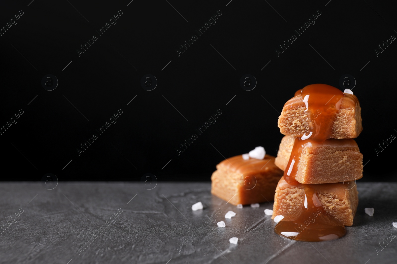 Photo of Salted caramel on grey table against black background. Space for text