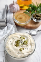 Photo of Tasty tartar sauce and ingredients on white table