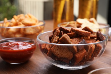 Crispy rusks and dip sauce on wooden table, closeup