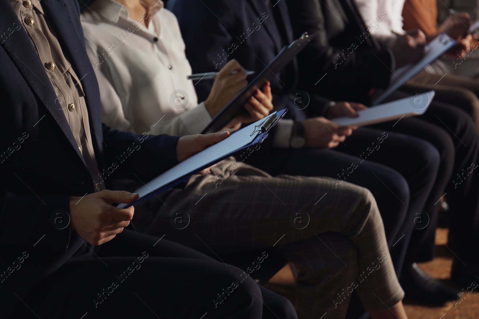 Photo of Young woman with clipboard waiting for job interview in office hall, closeup