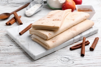 Photo of Board with raw wheat dough on wooden table