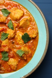 Delicious chicken curry on blue wooden table, top view