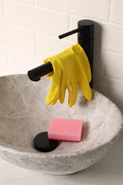Photo of Rubber gloves on faucet in bathroom sink