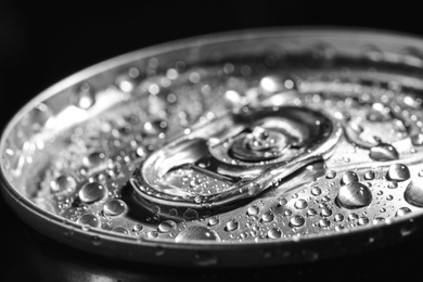 Photo of Aluminum can of beverage covered with water drops on black background, closeup