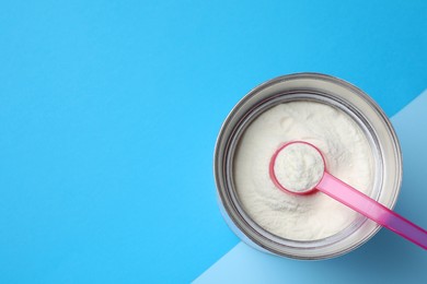 Photo of Can of powdered infant formula and scoop on color background, top view with space for text. Baby milk