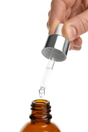 Photo of Woman holding pipette with oil over bottle on white background