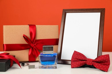 Photo of Happy Father's Day. Empty frame and presents on white table, closeup. Space for text