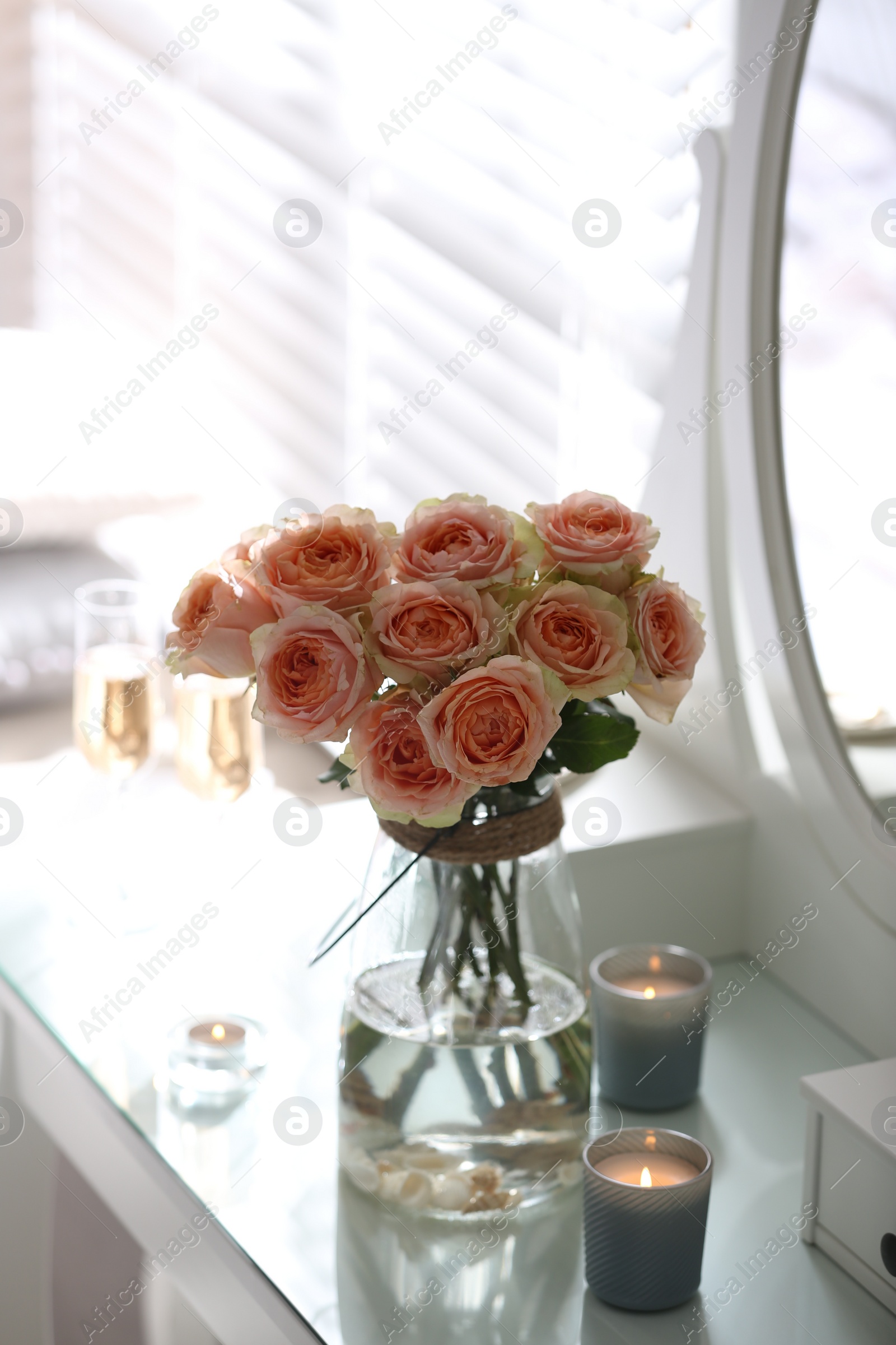 Photo of Glass vase with beautiful flowers on dressing table in modern room interior