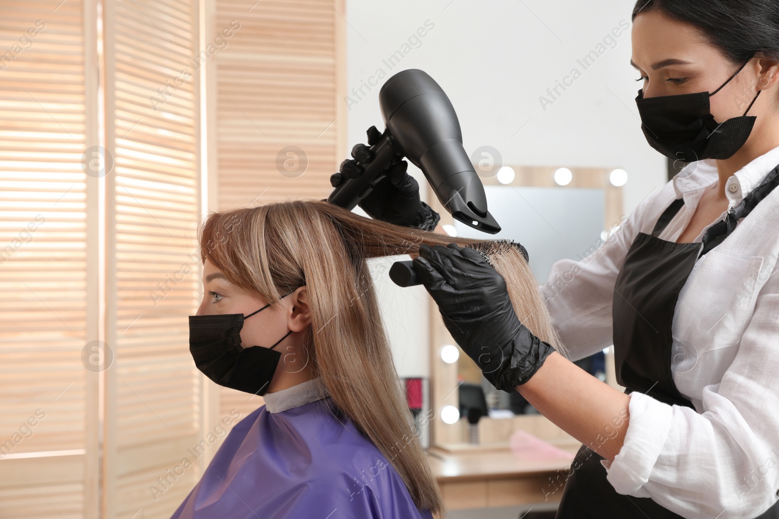 Photo of Professional stylist working with client in beauty salon. Hairdressing services during Coronavirus quarantine