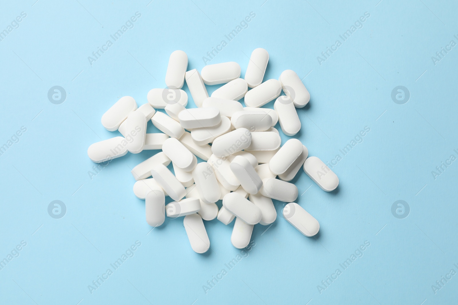 Photo of Vitamin pills on light blue background, top view