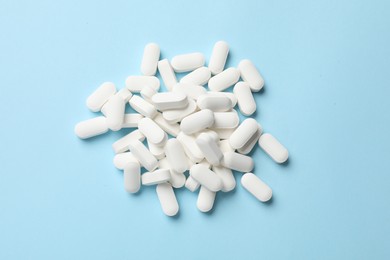 Photo of Vitamin pills on light blue background, top view