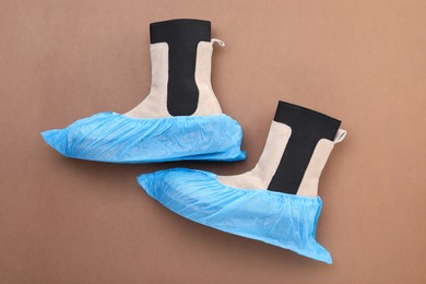 Women's boots in shoe covers on brown background, top view