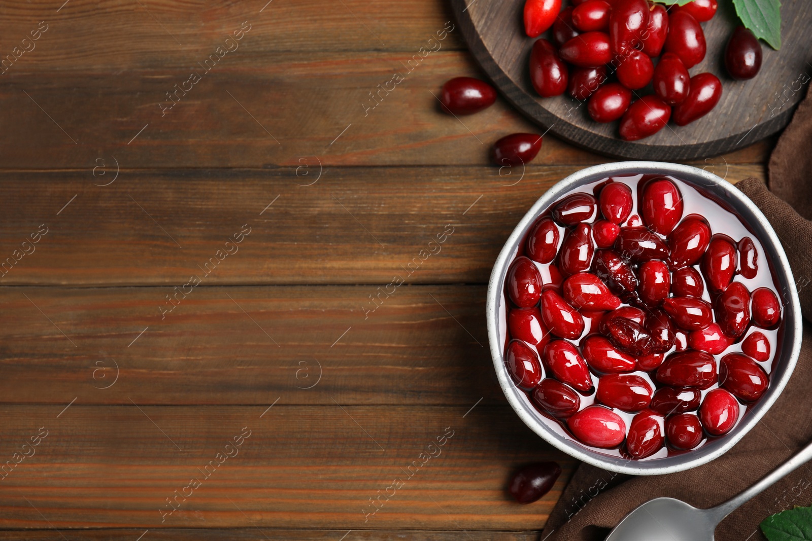 Photo of Delicious dogwood jam with berries on wooden table, flat lay. Space for text