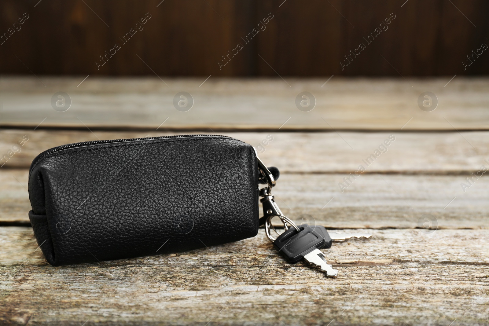 Photo of Leather case with keys on old wooden table, closeup. Space for text