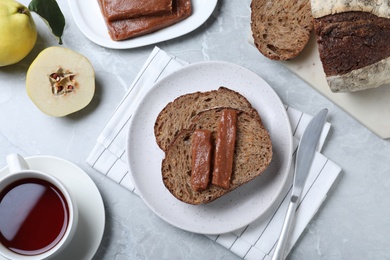 Photo of Tasty sandwich with quince paste served for breakfast on light grey marble table, flat lay