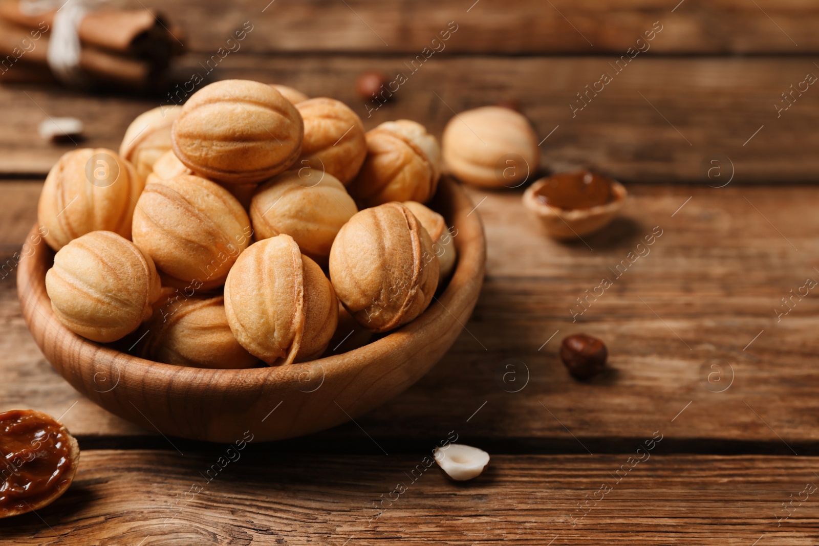 Photo of Homemade walnut shaped cookies with boiled condensed milk on wooden table. Space for text