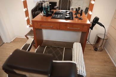 Stylish hairdresser's workplace with armchair, professional tools and cosmetic products in barbershop, above view