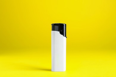 Photo of Stylish small pocket lighter on yellow background