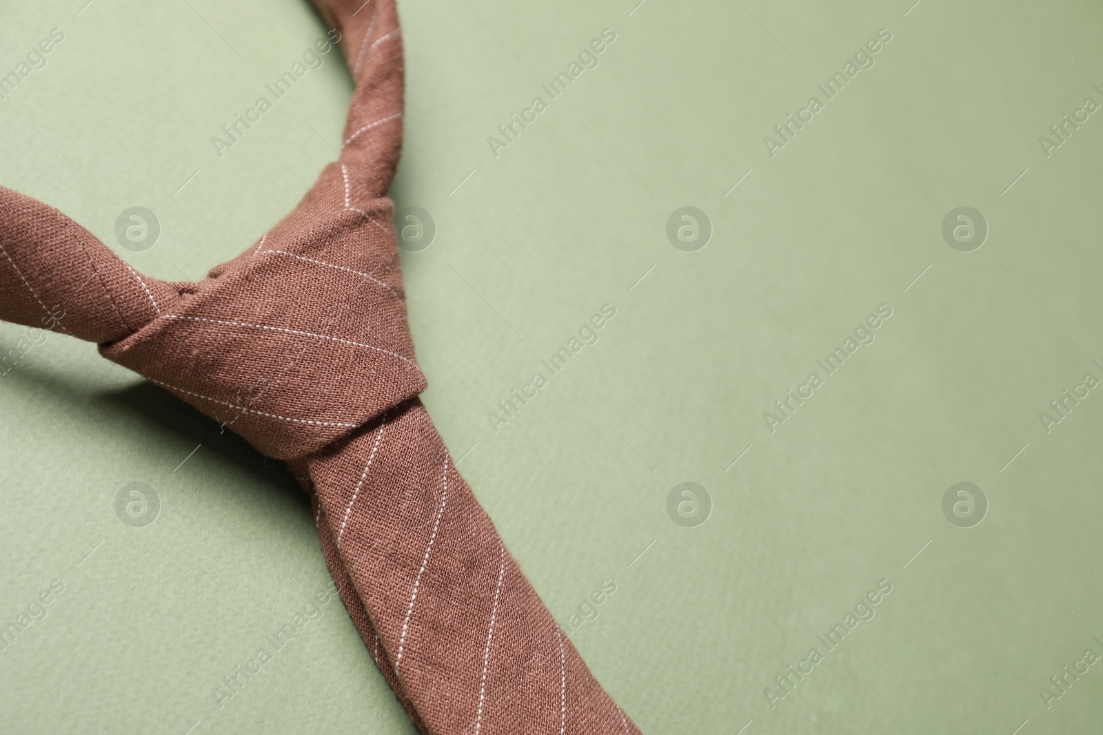 Photo of Stylish necktie on light green background, closeup. Space for text