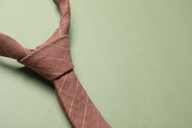 Stylish necktie on light green background, closeup. Space for text