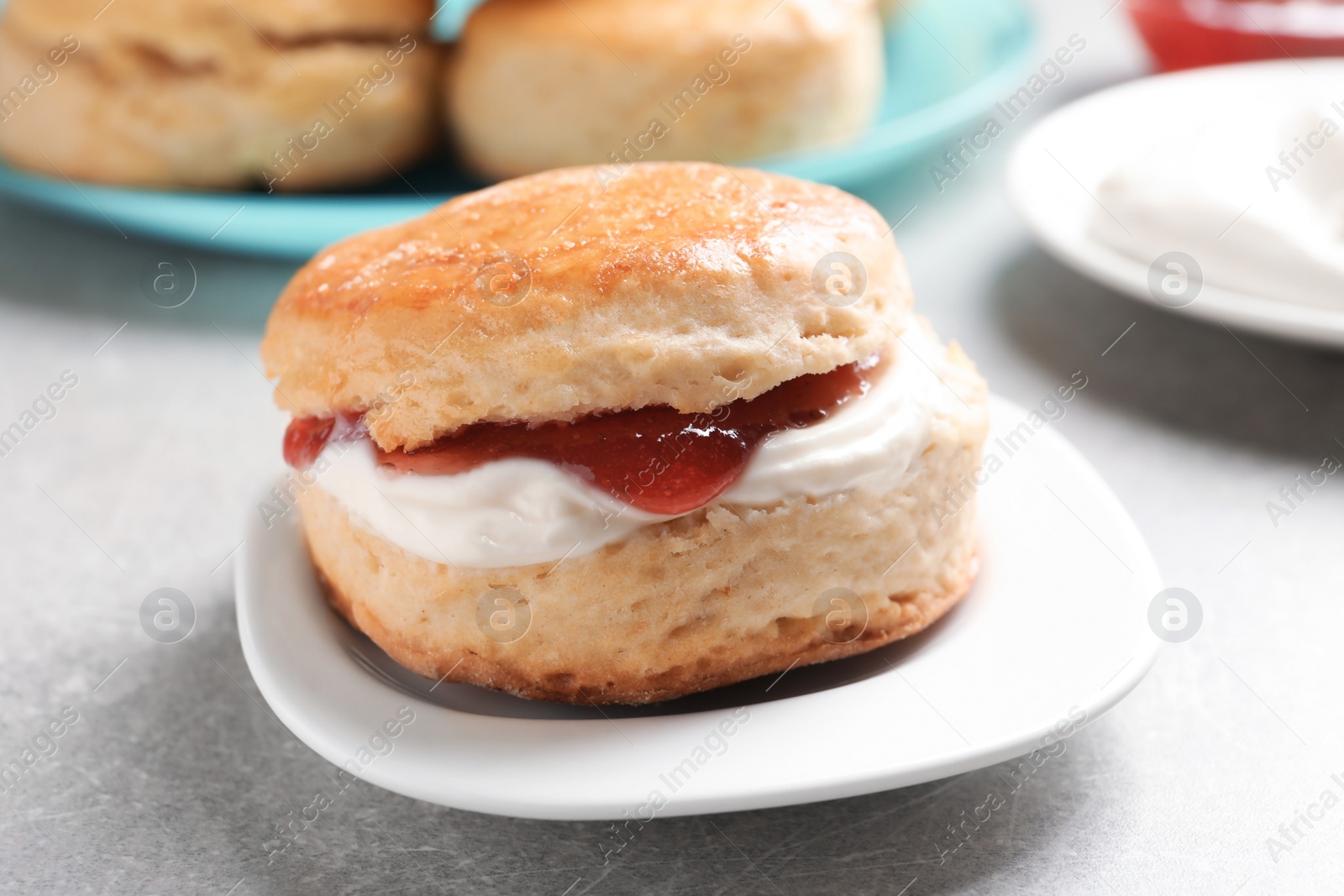 Photo of Tasty scone with clotted cream and jam on plate, closeup