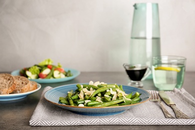 Photo of Plate with tasty green beans and almonds on table