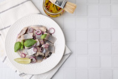 Plate with tasty fish, onion and marinade on light tiled table, flat lay. Space for text